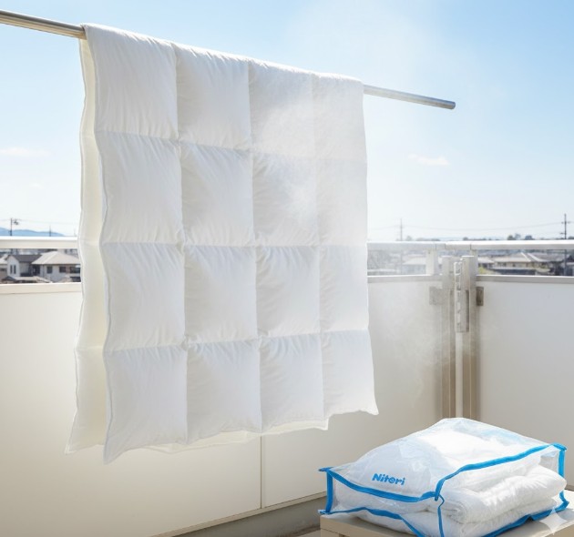 完全に乾燥させ熱が冷めた清潔な布団を圧縮袋に丁寧に詰める様子