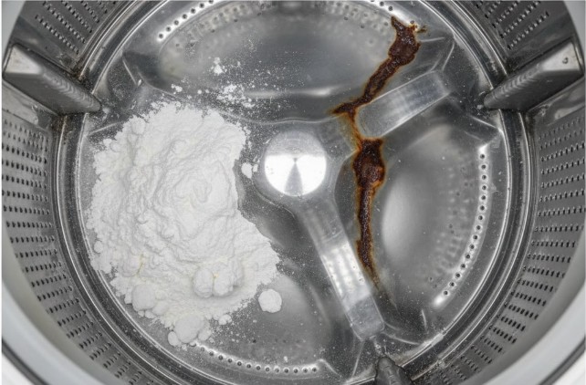 洗濯槽の底に残った溶けきらない重曹の粉末と、サビのイメージ。重曹やクエン酸の使用が洗濯機の故障リスクにつながることを警告する様子。